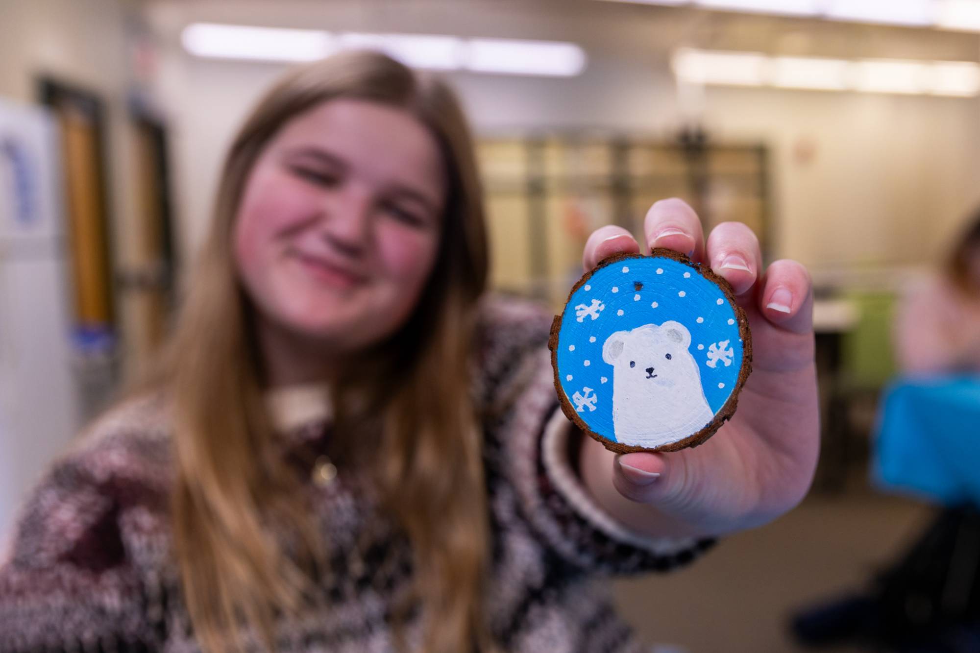 A student holding up a wooden circle with a polar bear painted onto it